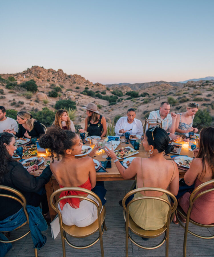 Group of friends hanging out around a dinner table during an event hosted on-site at ULUM Moab
